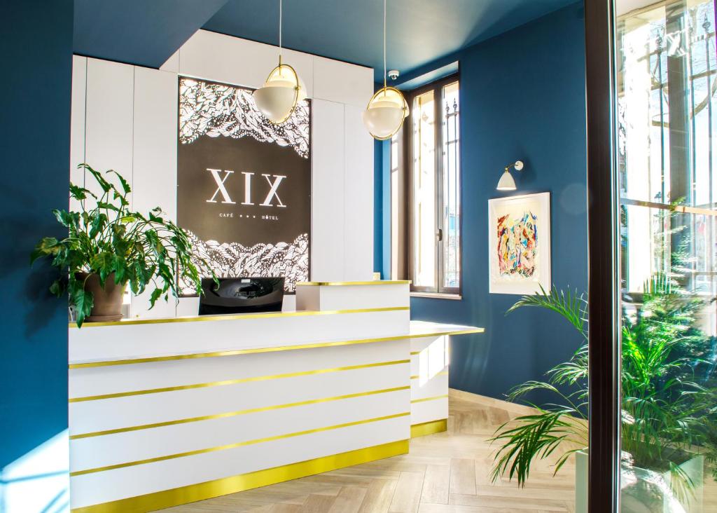 un hall avec des murs bleus et un comptoir blanc avec des plantes dans l'établissement Hôtel le XIX, à Béziers