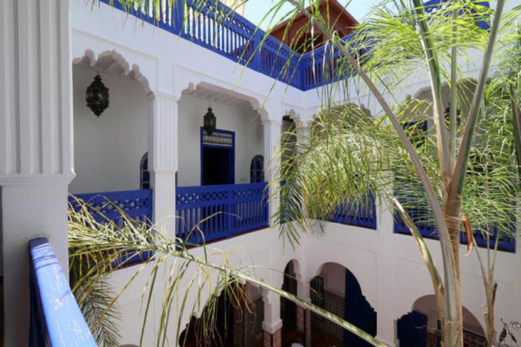 a blue and white building with palm trees in front of it at Riad Dar Colline in Marrakesh