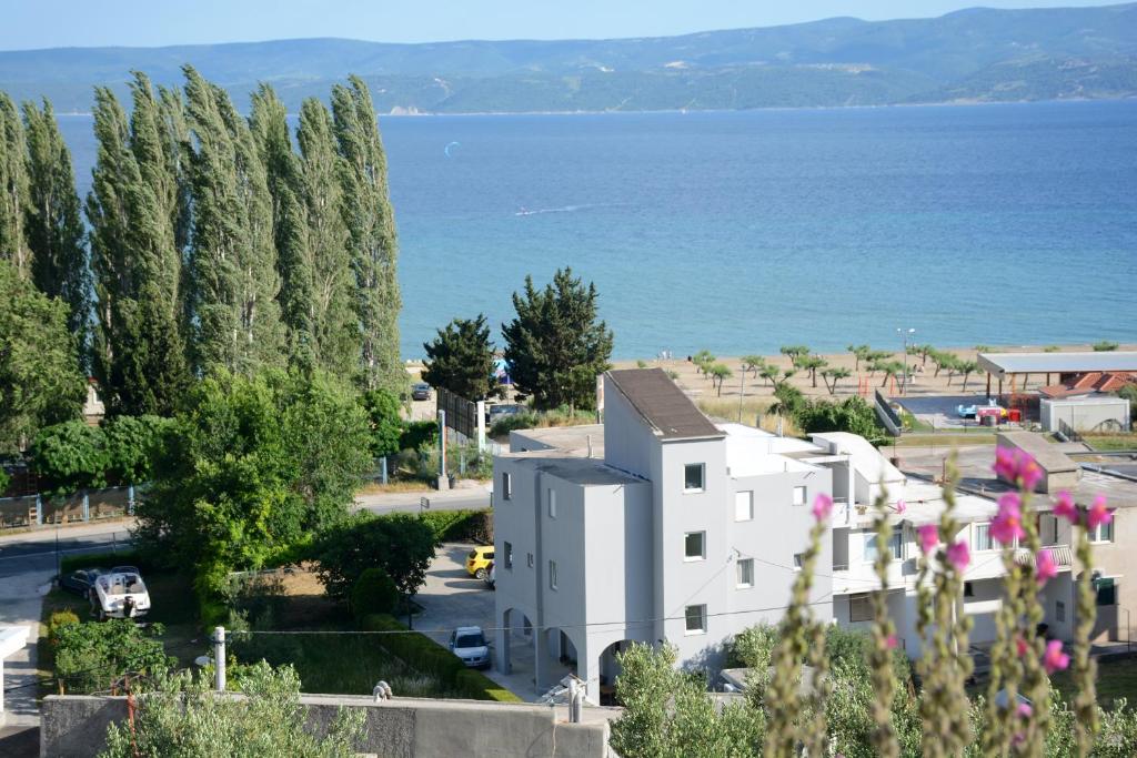 a building with trees and the ocean in the background at Apartments Ante in Omiš