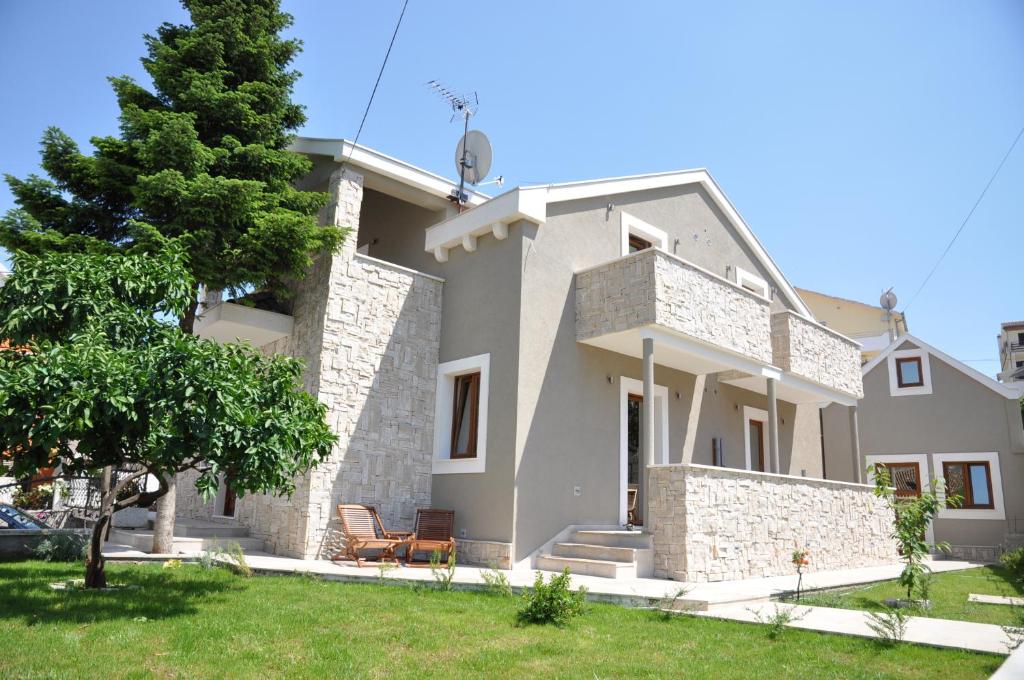 een groot wit huis met een boom in de tuin bij Villa Lučica Trogir in Trogir