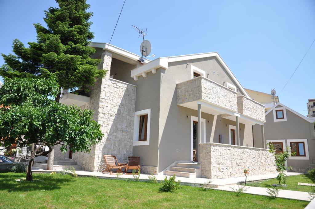 a large white house with a tree in the yard at Villa Lučica Trogir in Trogir