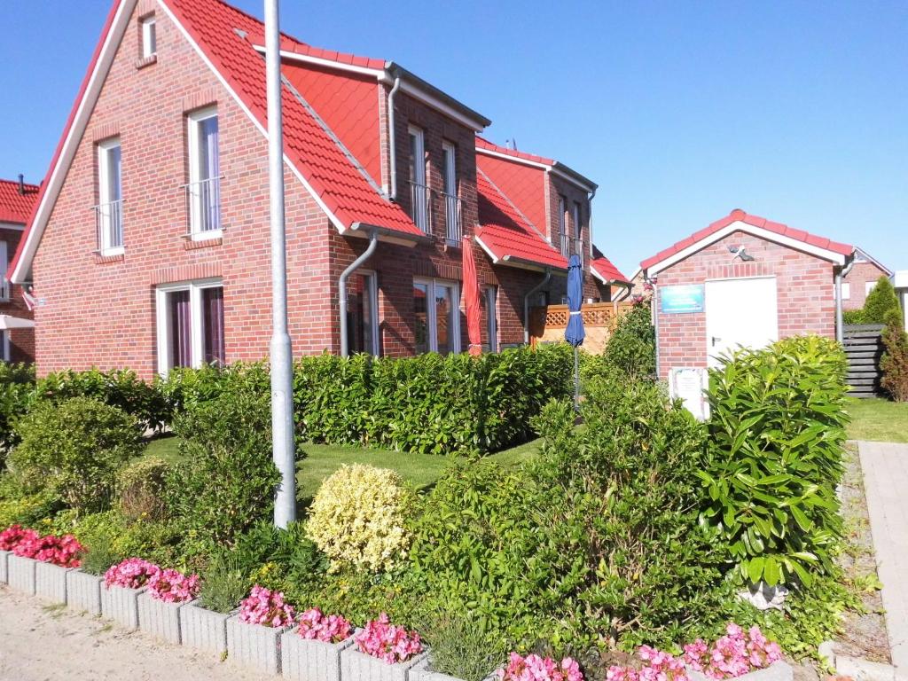 una casa de ladrillo rojo con flores delante en Ferienhaus Brigitte, en Carolinensiel