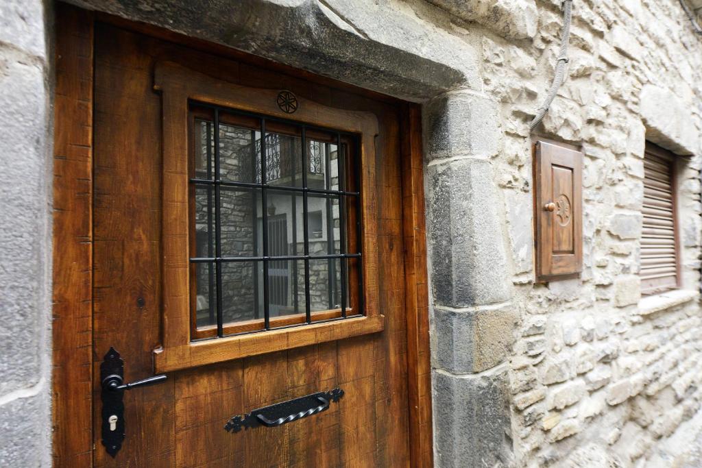 eine Holztür mit einem Fenster auf einem Steingebäude in der Unterkunft Casa Borruel in Torla-Ordesa