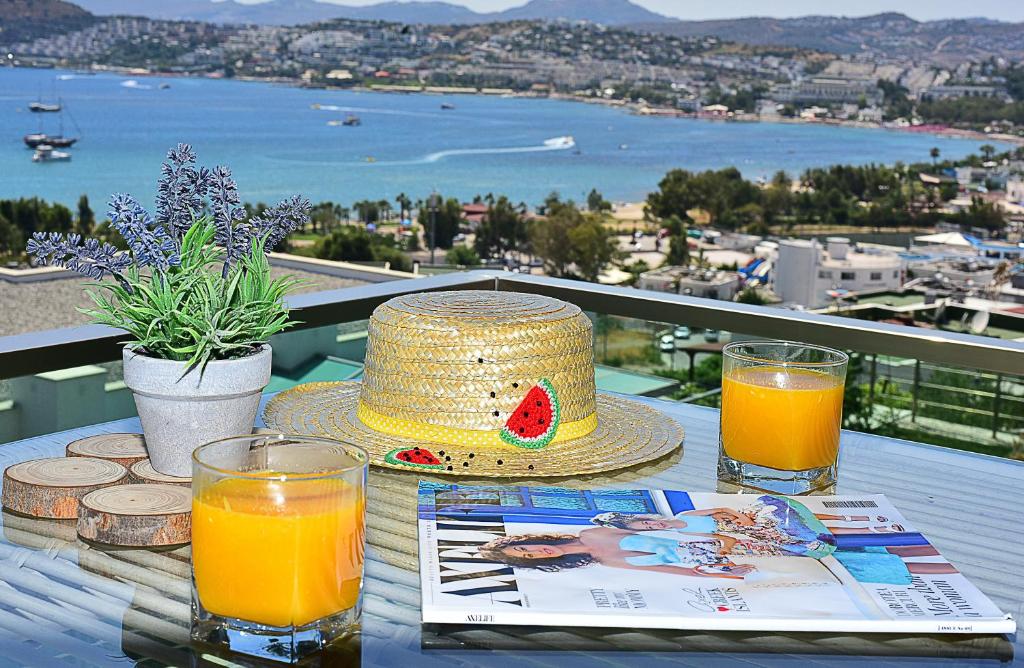 a table with a straw hat and two glasses of orange juice at Degirmenburnu Residence in Bodrum City