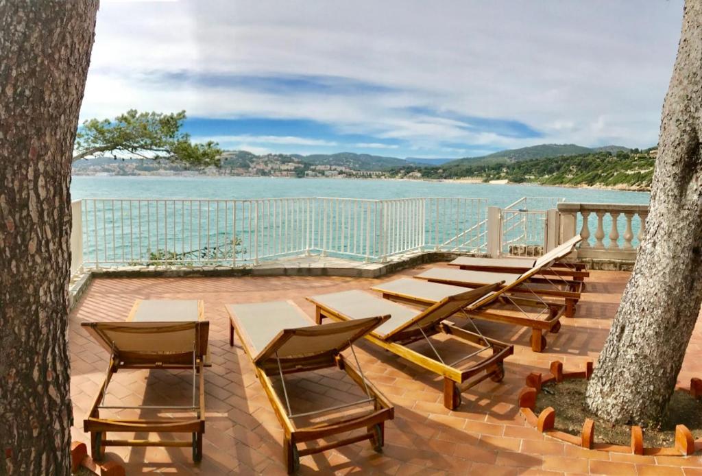 un grupo de sillas y mesas en una terraza con vistas al agua en Peyrascas, en Sanary-sur-Mer