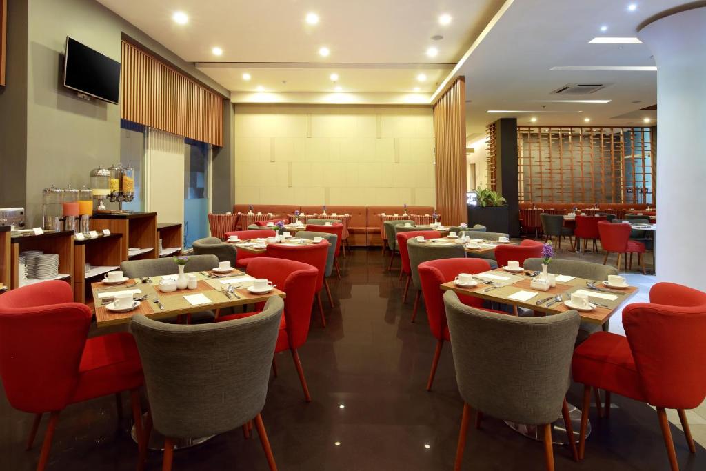 a restaurant with wooden tables and red chairs at Kyriad Hotel Airport Jakarta in Tangerang