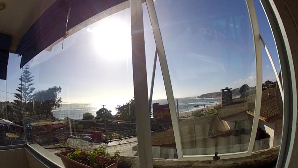 a window with a view of a beach and the ocean at Hostal Boutique F in El Quisco