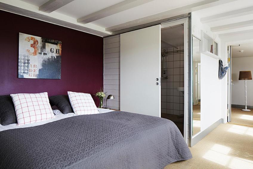 1 dormitorio con 1 cama con pared morada en Gotland Magazin1 Guesthouse en Havdhem