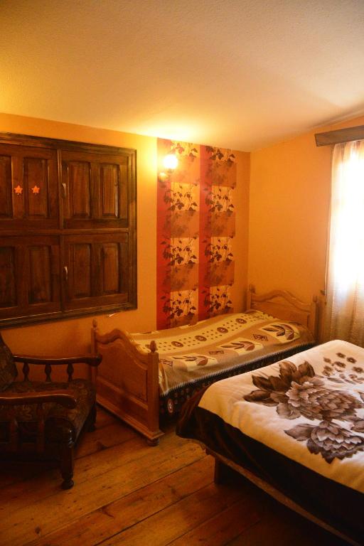 a bedroom with two beds and a cabinet and a window at Archil and Nino Gigauri Guest House in Stepantsminda