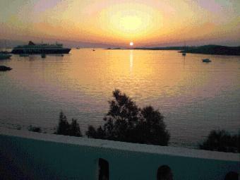 a sunset over a lake with a boat in the water at Hotel Paros in Parikia