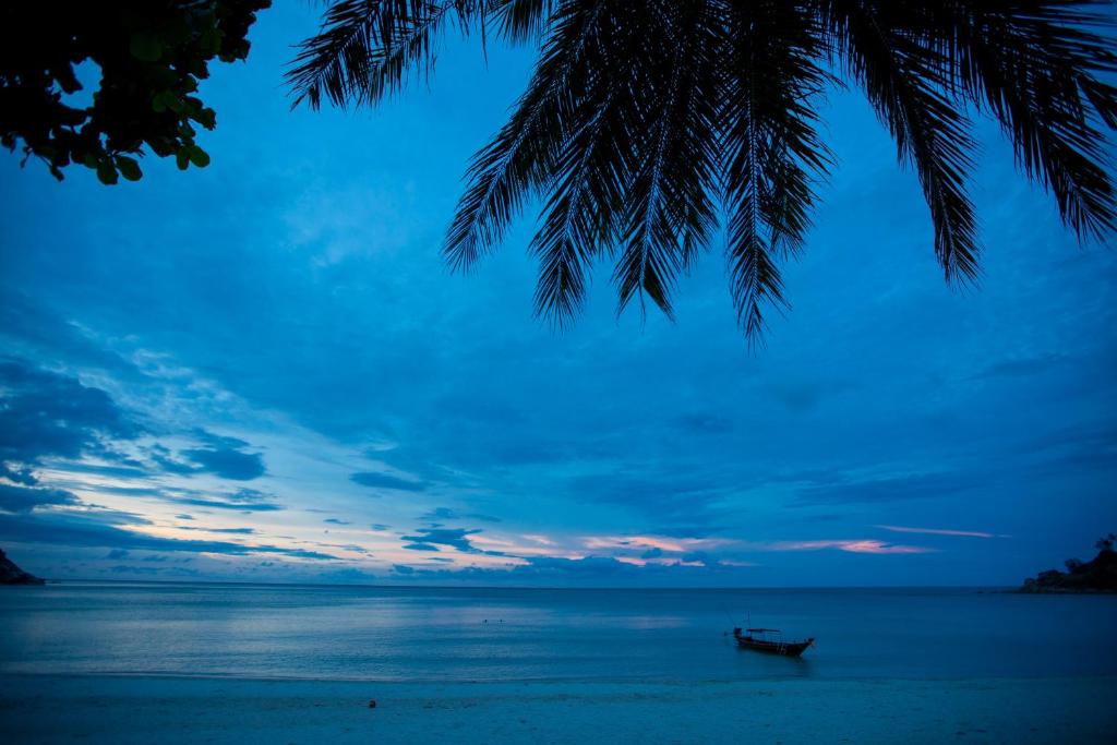 a boat on the beach with a sunset at Bottle Beach 1 Resort in Bottle Beach