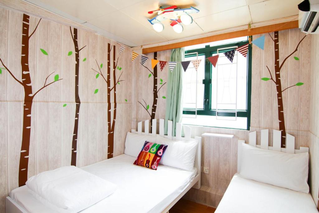 a room with two white beds and trees on the wall at Cozy Inn Jordan Station in Hong Kong