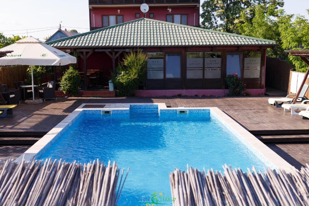 a swimming pool with umbrellas next to a house at Pension Delta Miraj in Sulina