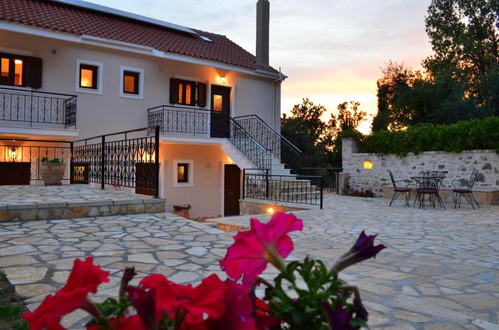 una casa con un patio de piedra con flores rojas en el primer plano en Casa Marina en Sivota