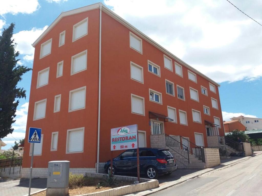 een rood gebouw met een auto ervoor geparkeerd bij Apartman PETRA in Trogir