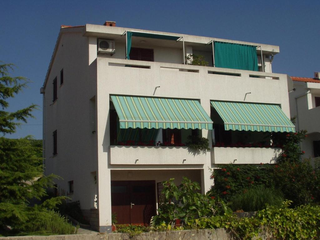 a white building with a green awning on it at Apartments Mrak in Punat