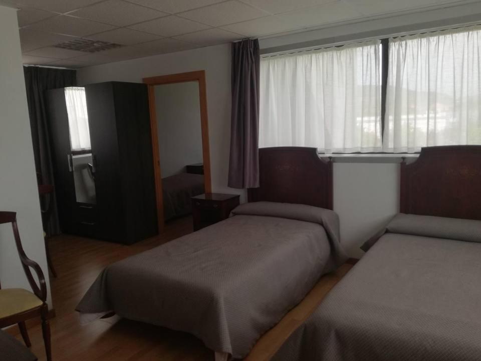 a hotel room with two beds and a window at Pension La Espiga in Pamplona