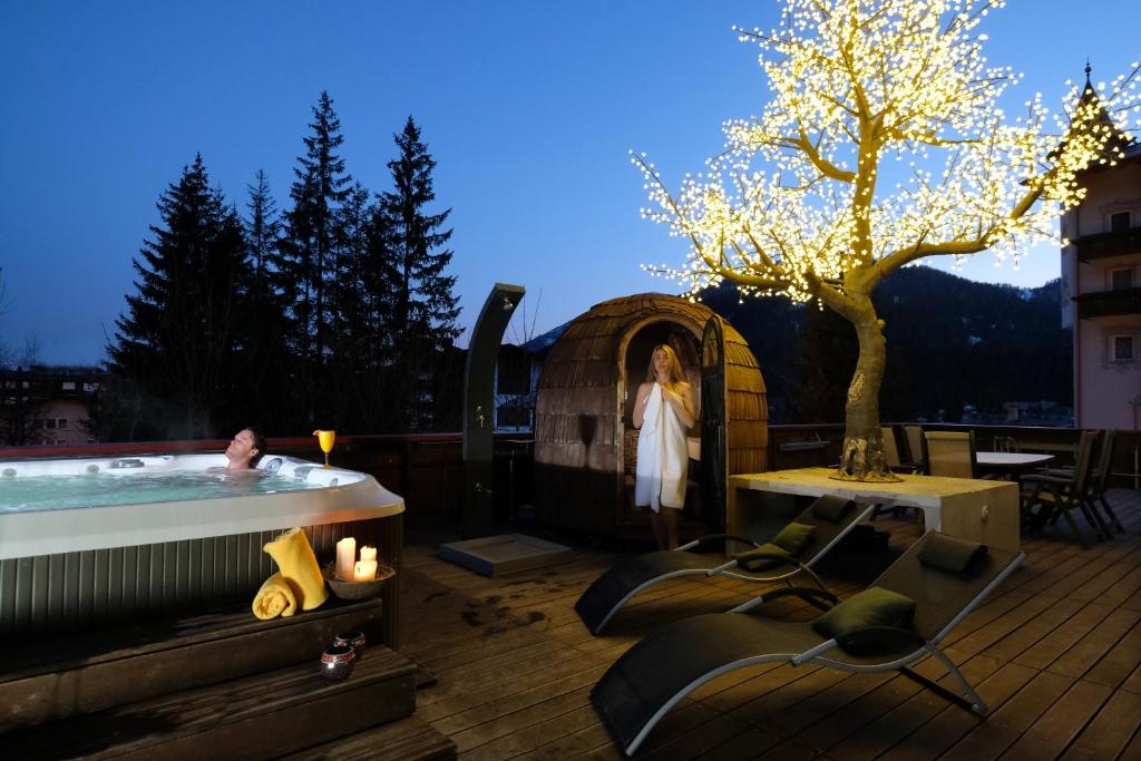 a woman standing next to a hot tub on a deck at Hotel Regina in San Martino di Castrozza