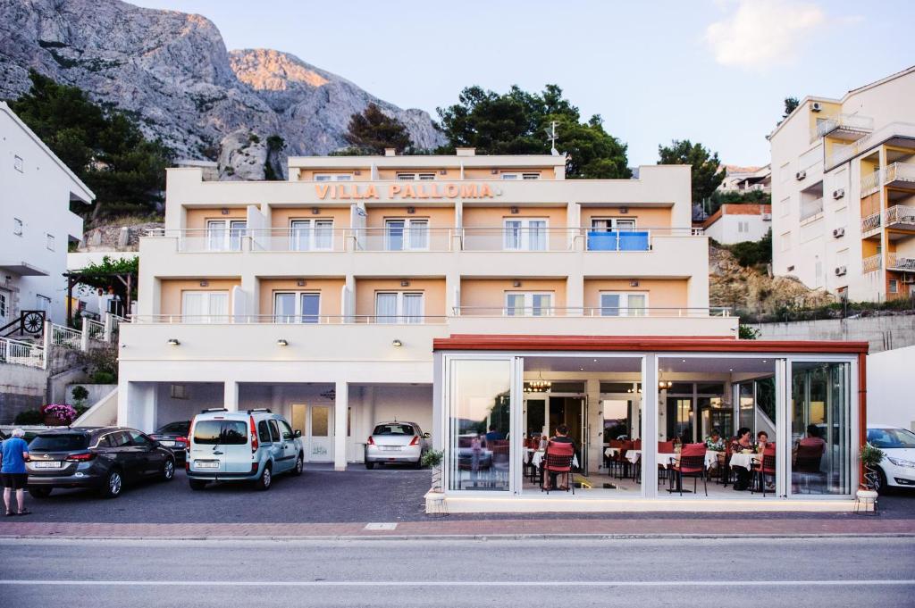 a building with cars parked in a parking lot at Villa Palloma in Baška Voda