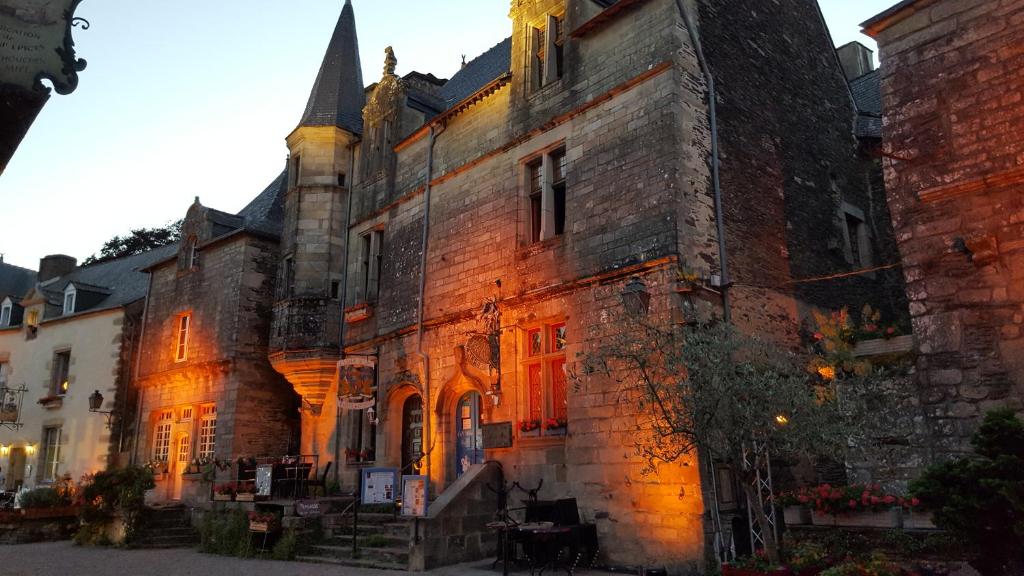 an old brick building with the light shining on it at La Tour du Lion in Rochefort-en-Terre