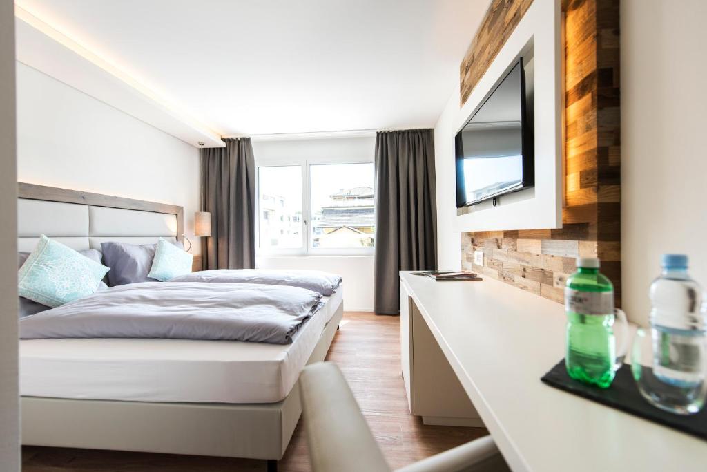 a bedroom with a bed and a desk with a television at Hotel Tilia in Uster