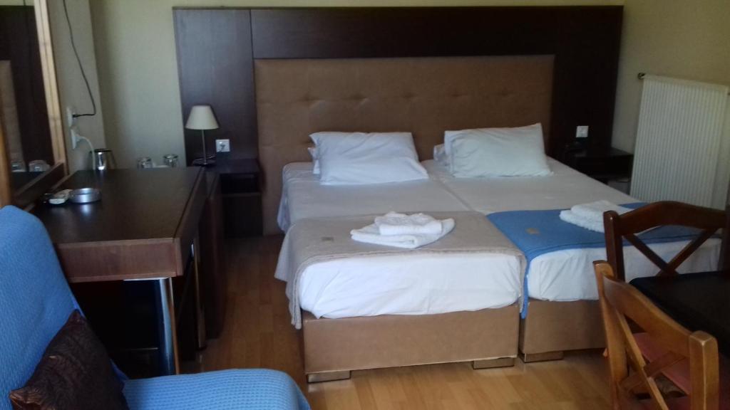 ein Hotelzimmer mit 2 Betten, einem Schreibtisch und einem Bett in der Unterkunft Parthenon Hotel in Souda