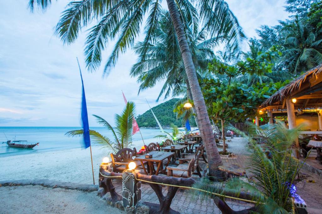 a restaurant on the beach with palm trees and the ocean at Bottle Beach 1 Resort in Bottle Beach