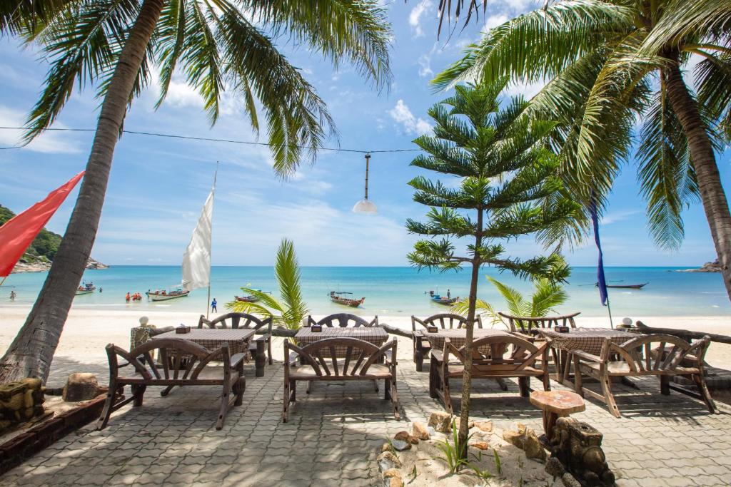 a cafe on the beach with palm trees and the ocean at Bottle Beach 1 Resort in Bottle Beach