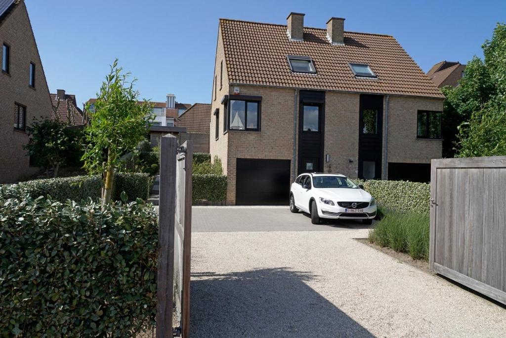 une voiture blanche garée devant une maison dans l'établissement Vakantiehuis Zand en Zee in Oostduinkerke aan zee, à Oostduinkerke