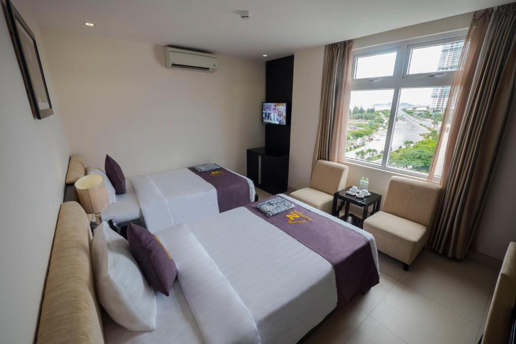 a hotel room with two beds and a window at Azumaya Hotel Da Nang in Danang