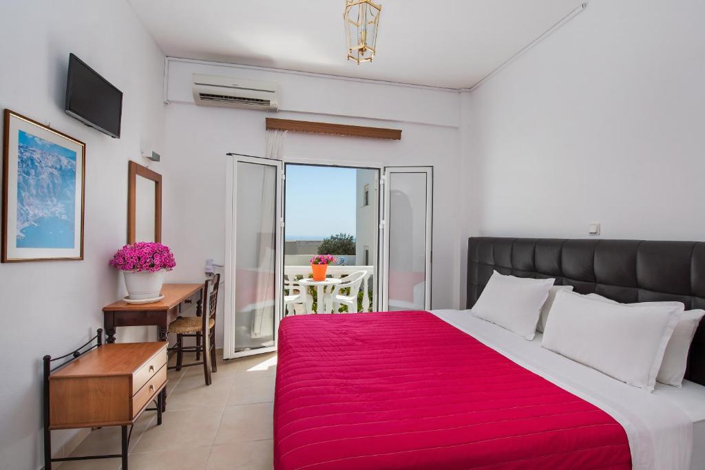 una camera da letto con un grande letto con una coperta rossa di Pension Ptolemeos a Firà