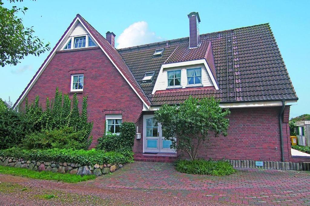 une maison en briques rouges avec un toit en gambrel dans l'établissement Haus-Meisennest-Wohnung-Kiebitz, à Westerland