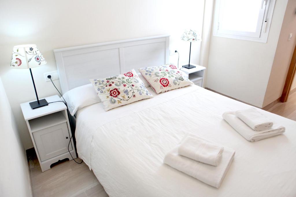 ein Schlafzimmer mit einem weißen Bett mit Kissen darauf in der Unterkunft Sleepin Sevilla Arenal in Sevilla