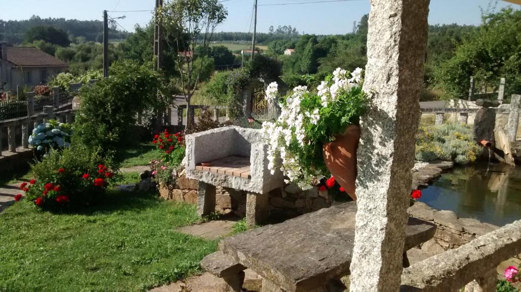 un jardín con flores en un jarrón sobre una pared de piedra en Casa Bartulo, en Castrofeito