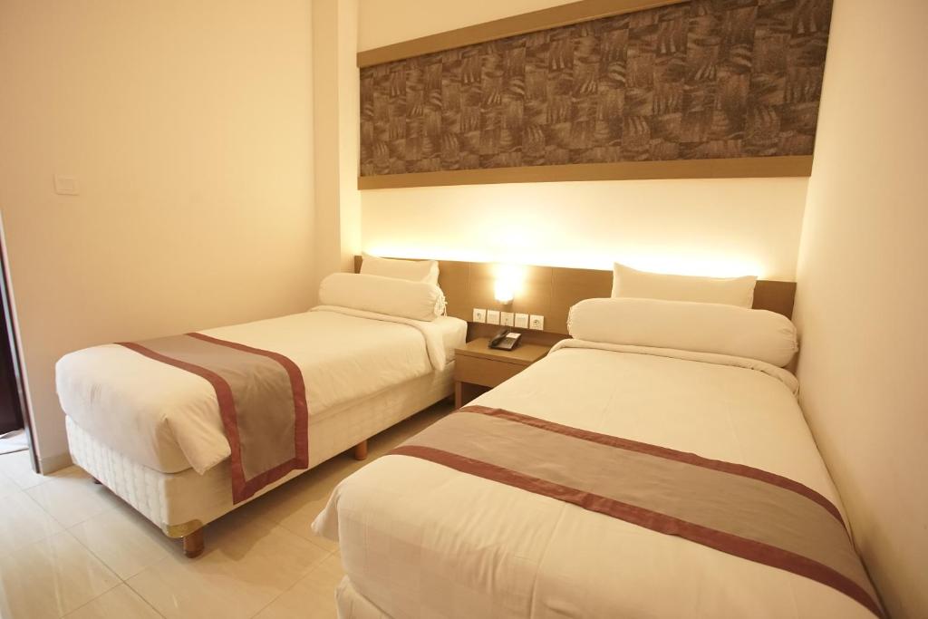 um quarto com duas camas num quarto de hotel em Viva Hotel Kediri by Azana em Kediri