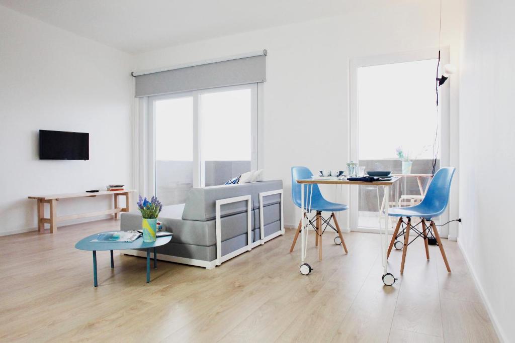 a white living room with blue chairs and a couch at Bite - Bike and Kite Accommodations in Trapani