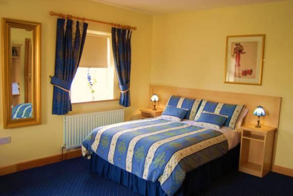 a bedroom with a bed and a window with blue curtains at Feerick's Hotel in Rathowen