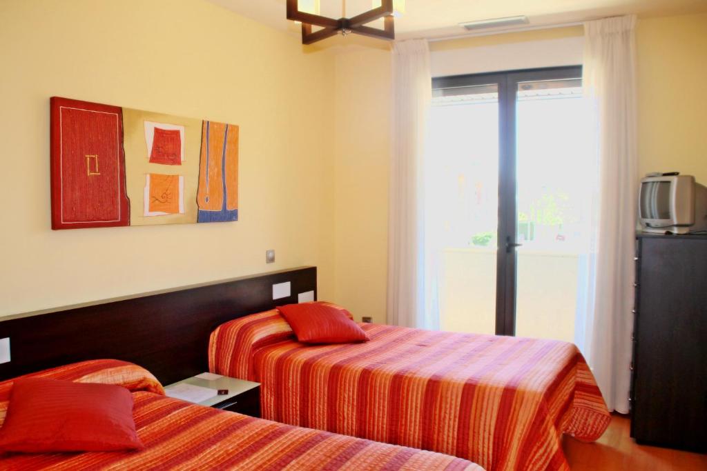 Habitación de hotel con 2 camas y ventana en Apartahotel Ribera en Arroyo de la Encomienda