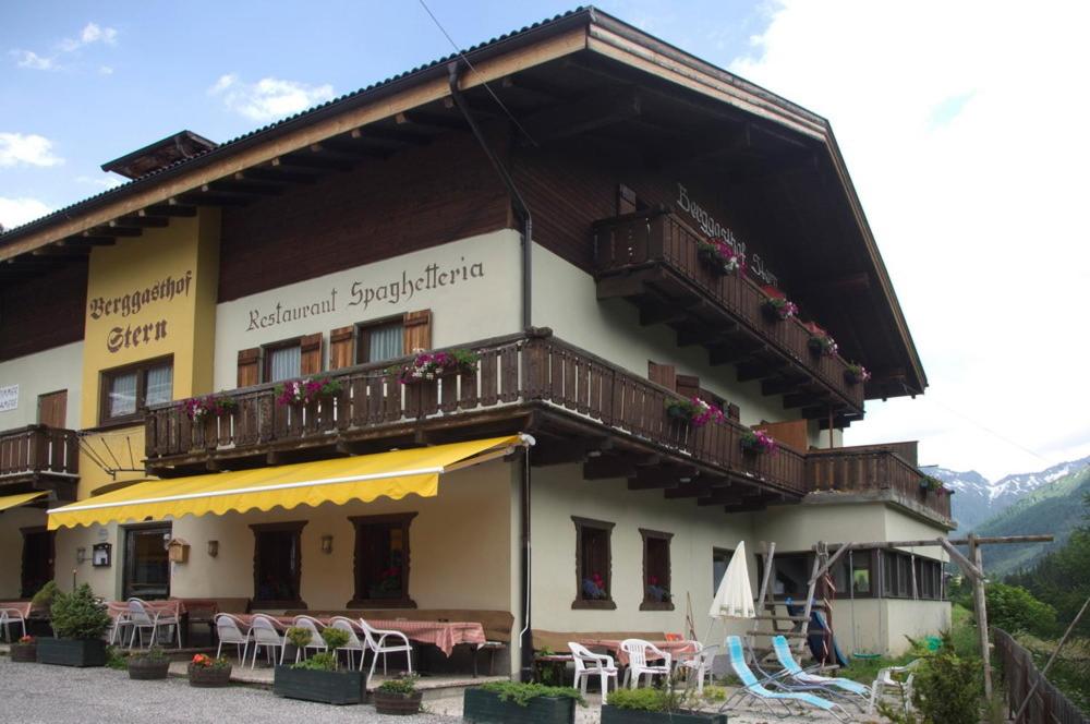 un edificio con balcón, mesas y sillas en Berggasthof Stern, en Predoi