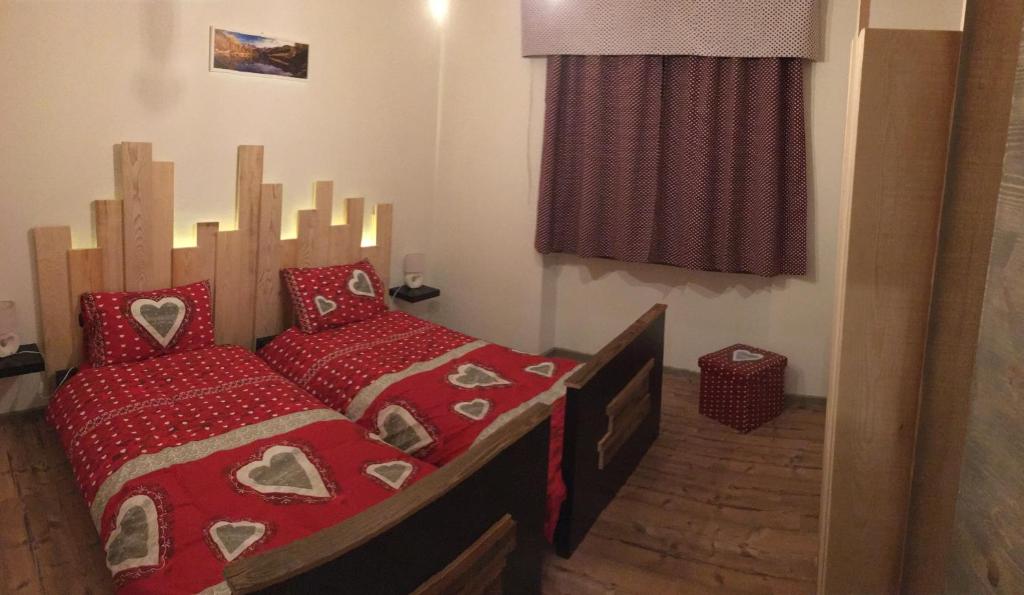 a bedroom with a bed with red sheets and red pillows at Le samantine in Baceno