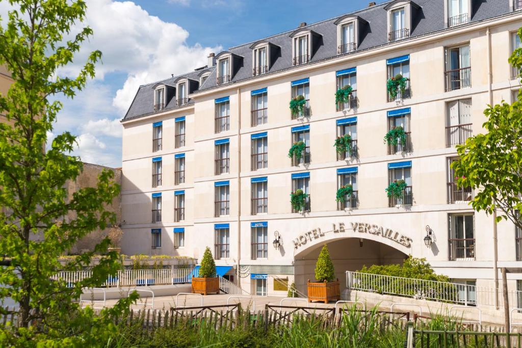 un grand bâtiment blanc avec des plantes sur lui dans l'établissement Hôtel Le Versailles, à Versailles