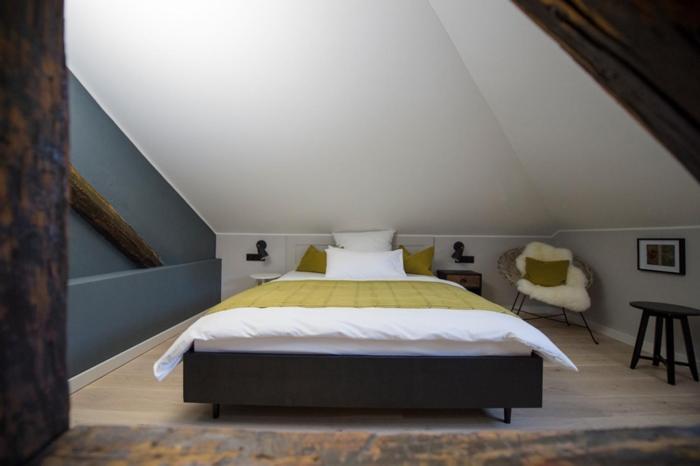 Villa Weiss في Helmbrechts: غرفة نوم بسرير وكرسي في العلية