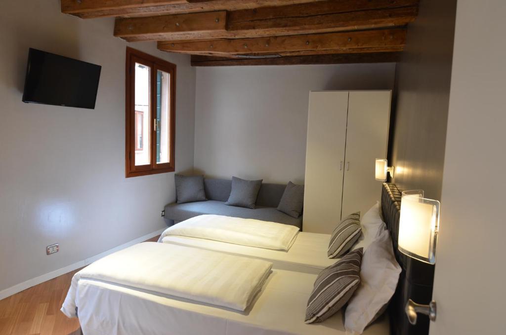 - une chambre avec deux lits et un canapé dans l'établissement Tiepolo Charme Houses, à Venise