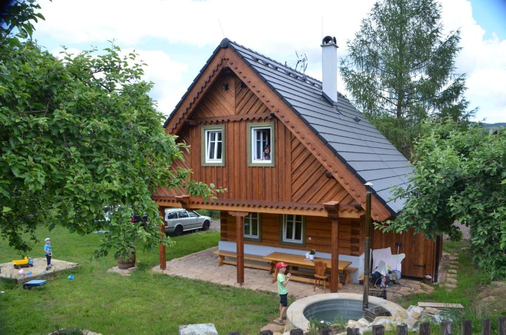 una pequeña casa de madera con gente parada frente a ella en Ubytování Na Vejminku en Rtyně v Podkrkonoší