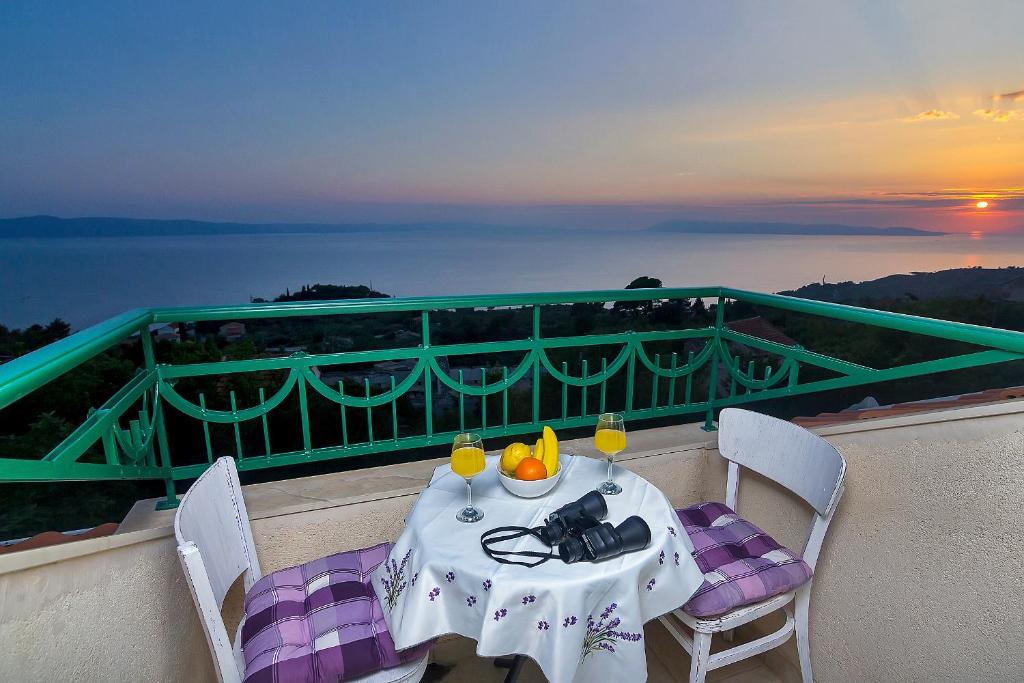 a table with two glasses of wine on a balcony at Villa Lavanda in Podgora