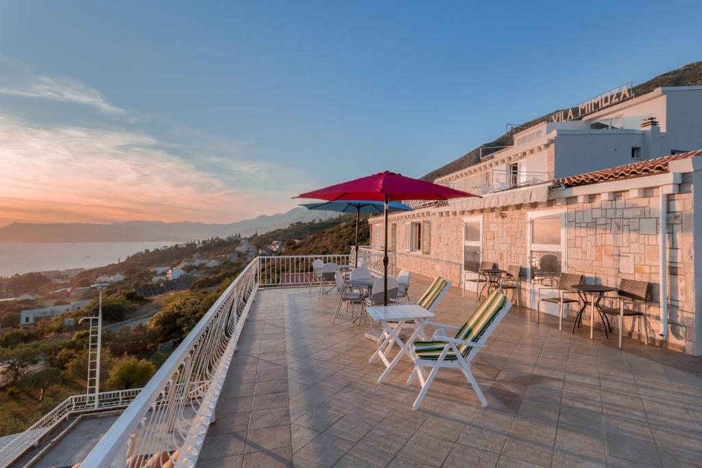 uma varanda com cadeiras, uma mesa e um guarda-sol em Villa Mimoza em Cavtat