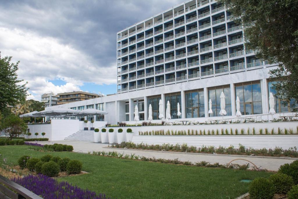 a white building with a garden in front of it at Makedonia Palace in Thessaloniki