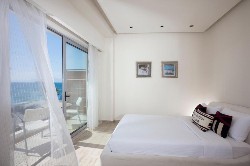 a white bedroom with a bed and a large window at Elite City Resort in Kalamata