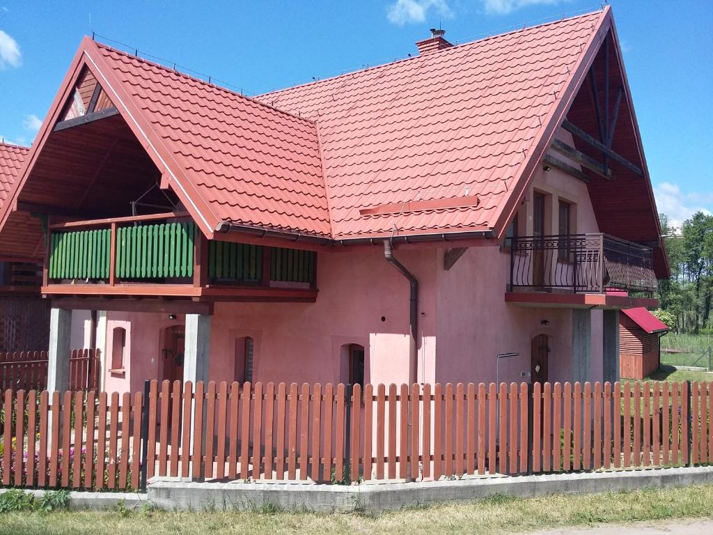 una casa con techo rojo y valla de madera en Domek Gościnny Natania en Jedwabno