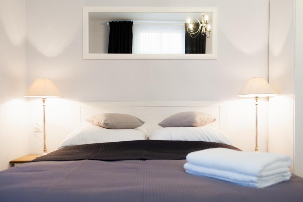 a bedroom with a bed with two lamps and a mirror at Pod Cisami Apartments in Międzyzdroje